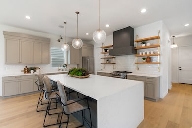 Kitchen with gray cabinets, decorative light fixtures, a kitchen breakfast bar, open shelves, and recessed lighting