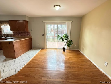 Kitchen featuring light countertops, backsplash, a peninsula, brown cabinetry, and light wood finished floors
