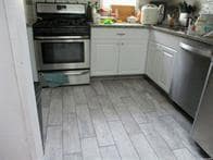 Kitchen featuring appliances with stainless steel finishes, light wood finished floors, and white cabinetry
