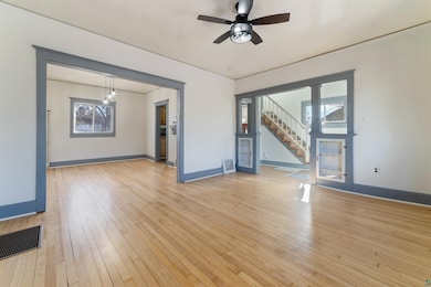 Unfurnished living room featuring visible vents, baseboards, light wood-type flooring, and stairs