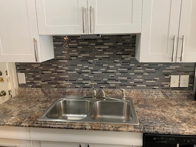 Kitchen with white cabinets, backsplash, and sink