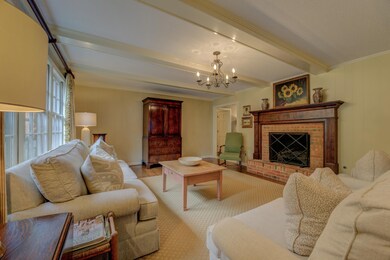 Den with a fireplace, crown molding, a chandelier,