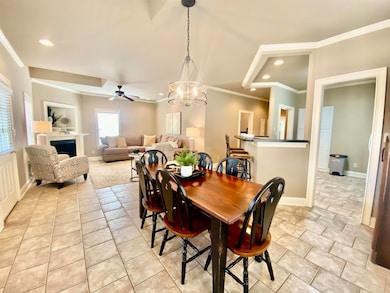 Dining room featuring crown molding, a chandelier, a fireplace, a ceiling fan, and recessed lighting