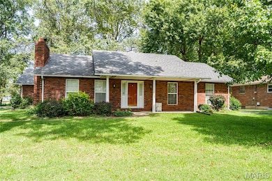 Single story home featuring a porch, a front lawn, a chimney, and brick siding