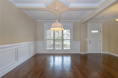 Unfurnished dining area featuring a chandelier, a decorative wall, a wainscoted wall, dark wood-style floors, and ornamental molding