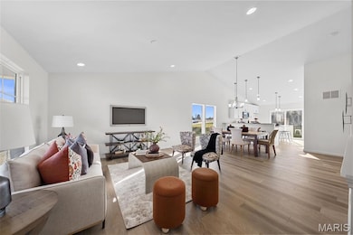 Living area featuring light wood finished floors, recessed lighting, high vaulted ceiling, and a chandelier