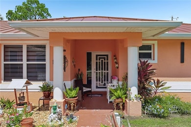 View of exterior entry featuring a standing seam roof, a metal roof, covered porch, and stucco siding