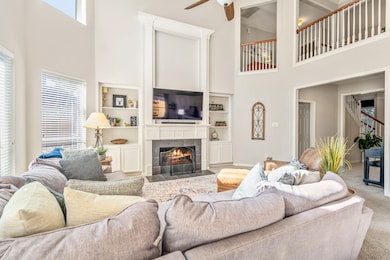 Bright and airy living area featuring soft carpeting, a cozy fireplace, and modern fixtures, open to the kitchen and breakfast nook for a natural gathering space.
