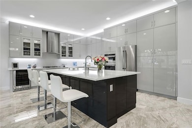 Kitchen featuring a large island, beverage cooler, wall chimney range hood, and recessed lighting