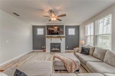 Living area with plenty of natural light, ceiling fan, a large fireplace, and light wood finished floors