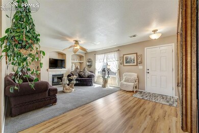Living area featuring ceiling fan, a textured ceiling, visible vents, wood finished floors, and a tile fireplace