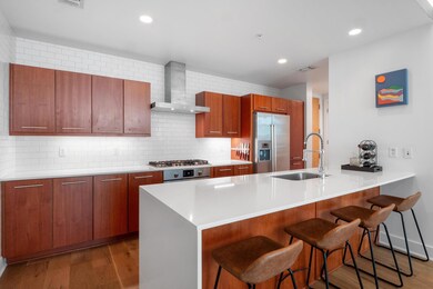 Kitchen with wall chimney range hood, a sink, a k