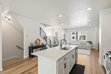 Kitchen with in-island smart sink, white cabinets, quartz counters, and an open floor plan