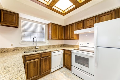 Kitchen with light stone countertops, sink, and wh
