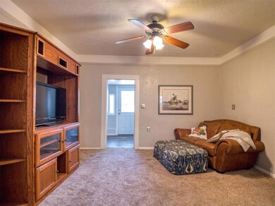 Living room with carpet, ceiling fan, and baseboards