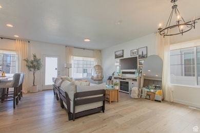 Living room with recessed lighting, light wood-style flooring, and a chandelier