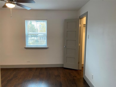 Unfurnished room featuring a ceiling fan, dark woo