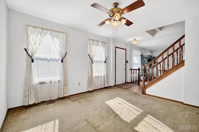 Foyer entrance with carpet flooring, stairs, and a ceiling fan