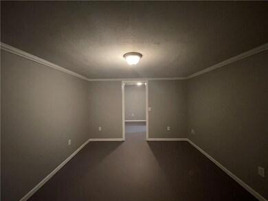 Empty room featuring dark colored carpet, baseboar