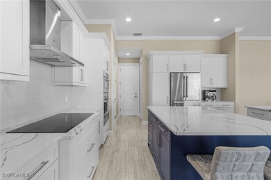 Kitchen featuring white cabinetry, wall chimney ra