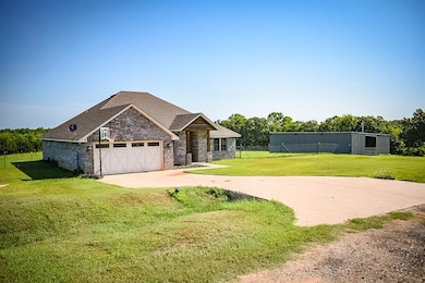 View of front facade featuring driveway, brick siding, a garage, and roof with shingles