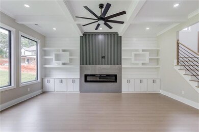Unfurnished living room featuring beam ceiling, light wood-type flooring, built in features, a fireplace, and coffered ceiling