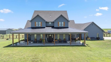 Rear view of house with a shingled roof, board and batten siding, french doors, and a patio area