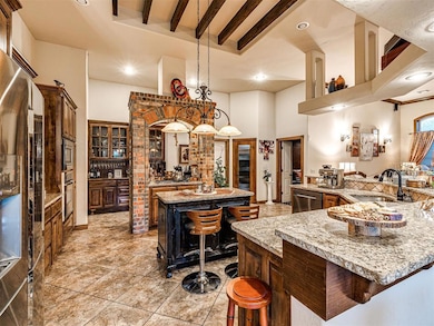 Kitchen featuring a sink, appliances with stainless steel finishes, a large island, a breakfast bar area, and light tile patterned floors