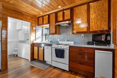 Kitchen featuring brown cabinets, white appliances, tasteful backsplash, dark wood-style floors, and recessed lighting