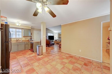 Kitchen featuring crown molding, light countertops, freestanding refrigerator, open floor plan, and a sink