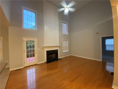 Unfurnished living room with high vaulted ceiling, a ceiling fan, a fireplace with flush hearth, and wood finished floors