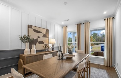 Dining space featuring wood finished floors, a decorative wall, recessed lighting, and crown molding