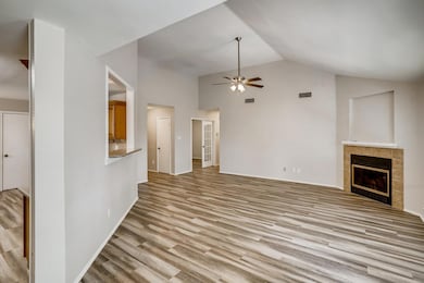 Unfurnished living room featuring a fireplace, light wood finished floors, a ceiling fan, and high vaulted ceiling