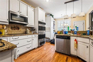 Kitchen featuring appliances with stainless steel finishes, a sink, white cabinetry, tasteful backsplash, and light wood-type flooring