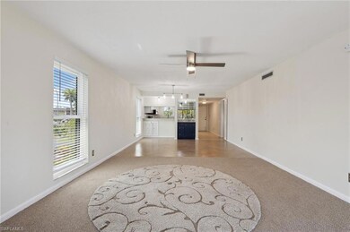 Unfurnished living room featuring light carpet, baseboards, and a ceiling fan