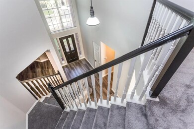 Carpeted entryway featuring a high ceiling and stairway