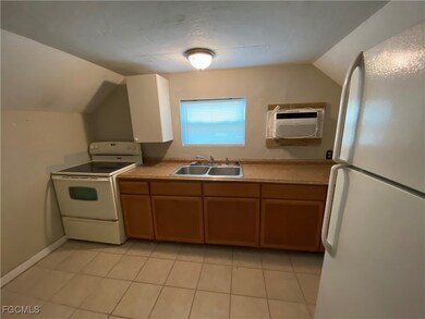 Kitchen with white appliances, lofted ceiling, light tile patterned floors, light countertops, and brown cabinets