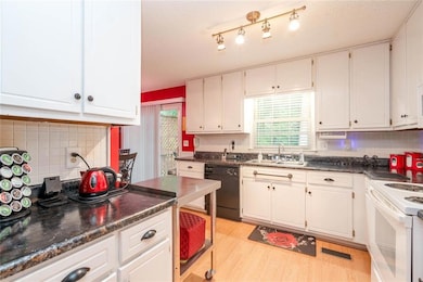 Kitchen with dishwasher, white range with electric cooktop, dark countertops, white cabinetry, and light wood-type flooring