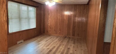 Spare room with a textured ceiling, ceiling fan, wood walls, and wood-type flooring