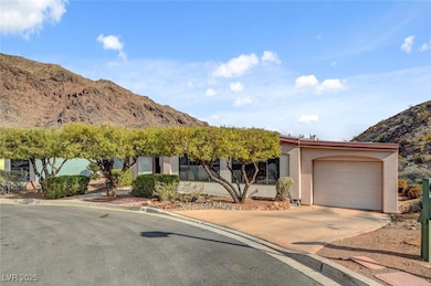 Obstructed view of property featuring concrete driveway, a mountain view, an attached garage, and stucco siding