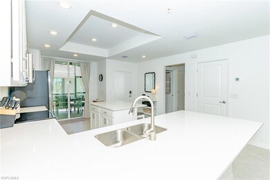 Kitchen featuring recessed lighting, a tray ceiling, white cabinetry, a kitchen island, and light countertops