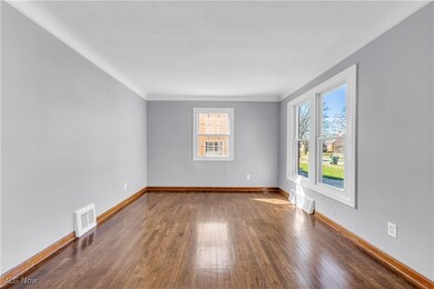 Unfurnished room featuring dark wood-type flooring, crown molding, baseboards, and visible vents