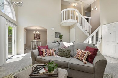 Living area featuring a towering ceiling, carpet flooring, a chandelier, arched walkways, and stairway