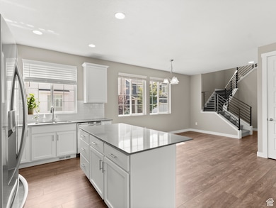 Kitchen featuring white cabinets, stainless steel fridge with ice dispenser, recessed lighting, pendant lighting, and tasteful backsplash