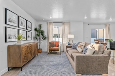 Living room featuring light wood-type flooring, a textured ceiling, and recessed lighting