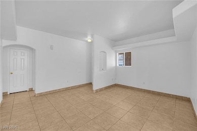 Unfurnished room featuring arched walkways and light tile patterned flooring