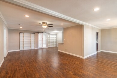 Bright and open living area featuring recessed lighting, beautiful flooring, and built-in shelving for storage or display