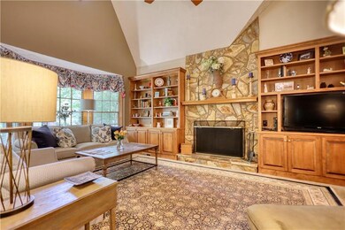 Living area featuring high vaulted ceiling, a fireplace, and a ceiling fan
