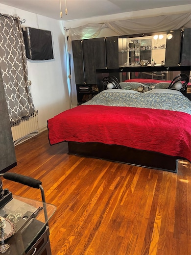Bedroom featuring radiator and wood finished floors