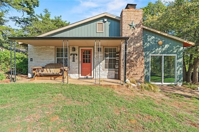 View of front of house with covered porch, a chimney, a front lawn, and stone siding